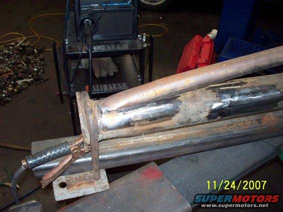 Welding a section of exhaust pipe with a welding machine and clamps nearby. Date stamp shows 11/24/2007