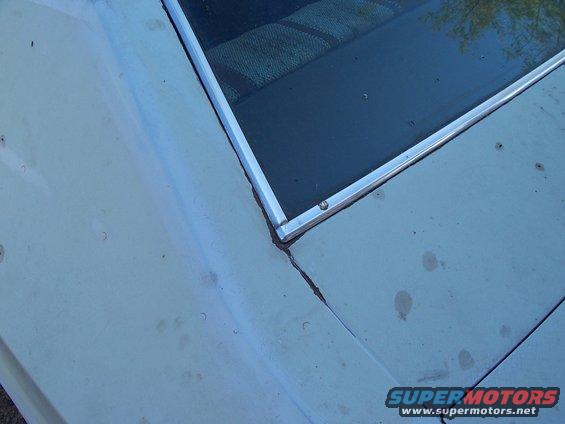 close-up of a car's rear window and roof panel, showing some dirt and wear
