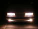 1991 Mazda MX-6 - The front of a car is illuminated by its headlights and fog lights in the dark.