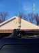 2007 Nissan Xterra - A vehicle's roof rack holds a tall antenna, with a house and trees visible under a clear blue sky.