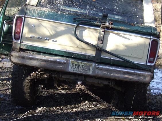 Rear view of a green and cream Ford pickup truck stuck in mud, with a New Jersey license plate