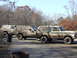 1979 Ford Bronco - Three muddy SUVs are parked on a dirt road, with bare trees and autumn foliage visible.