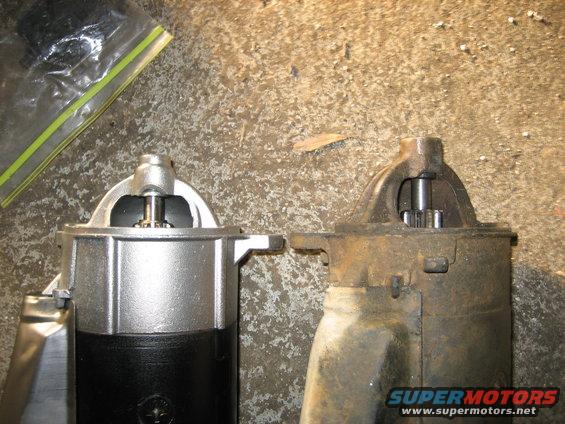 New starter motor next to old rusty one. Both have gears visible