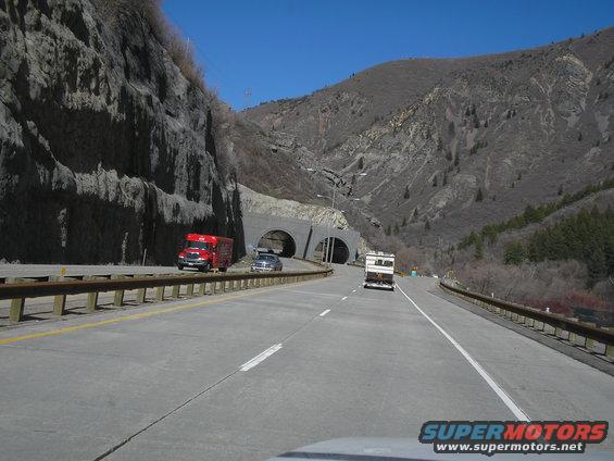 Red truck and RV on highway near tunnel entrance