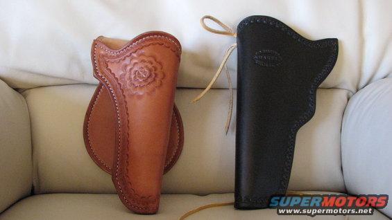 Two leather holsters, one tan with floral tooling, one black, resting on a light-colored surface