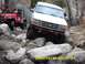 1996 Ford Bronco - A white 1996 Ford Bronco tackles a challenging rocky trail, with a red Jeep visible behind it.