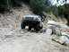 1996 Ford Bronco - A white Ford Bronco is shown off-roading on a challenging rocky terrain.