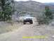 1996 Ford Bronco - A white 1996 Ford Bronco navigates a steep dirt trail in a mountainous, arid landscape.