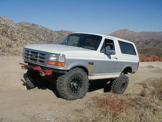 White and silver 1996 Ford Bronco with off-road tires on a dirt trail