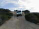 1996 Ford Bronco - A white SUV navigates a steep dirt path, its off-road capabilities under a cloudy sky.