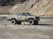 1993 Ford Bronco - This lifted pickup truck is parked in a dry, rocky area with hills in the background.