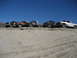 1993 Ford Bronco - A group of modified off-road vehicles are lined up on a dusty embankment.