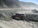 1993 Ford Bronco - A red and white SUV navigates a dusty, winding dirt track in a barren, mountainous area.