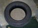 1994 Ford F-250 - A close-up view of a single tire, resting on a concrete surface next to a green mat.