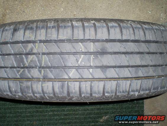 Tire tread with yellow and white markings, on a dark green surface