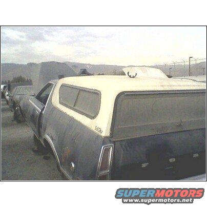 1973 Ford Ranchero with camper shell parked in a lot, other vehicles visible