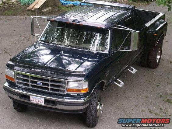 Dark blue 1993 Ford F-350 dually truck, parked outside with some construction materials in the background