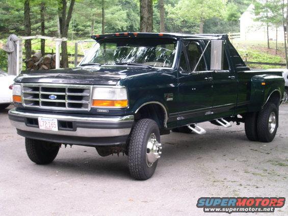 Dark green Ford F-350 dually truck with chrome grille and dual rear wheels, parked outdoors