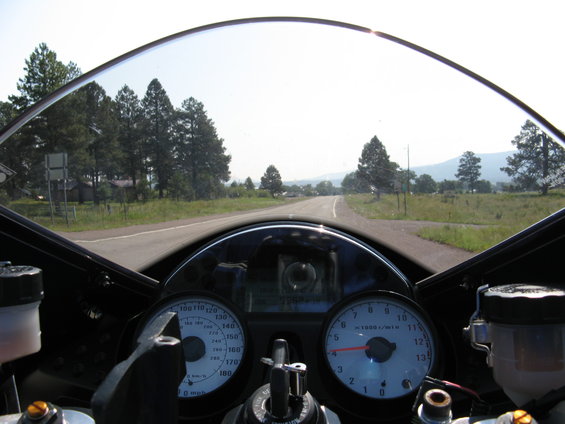 Motorcycle dashboard with speedometer and tachometer, view through windshield