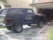1978 Ford Bronco - A black 1978 Ford Bronco is parked in front of a garage, with one front wheel on a yellow block.