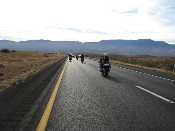 Motorcycles riding on a highway with mountains in the background