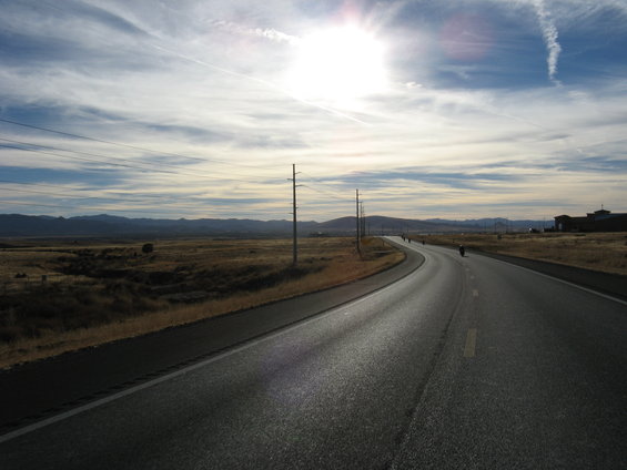 Motorcycles riding on a highway with a bright sun in the sky