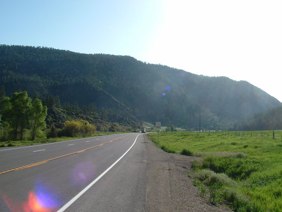 Highway with a speed limit sign of 60, a truck in the distance, and a forested mountain