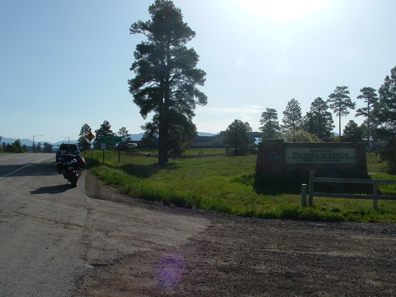 Motorcycle parked on roadside near Pagosa Springs sign. A car is visible in the background