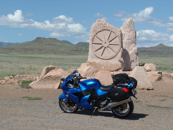 Blue 2007 Kawasaki Ninja motorcycle parked in front of a stone monument with a wheel carving