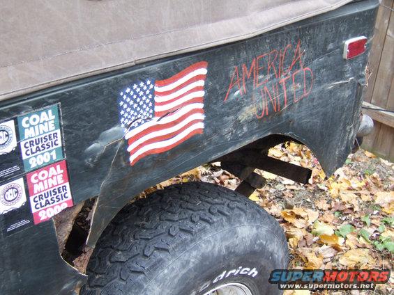 rear quarter panel of a weathered vehicle with American flag sticker and "AMERICA UNITED" painted on it