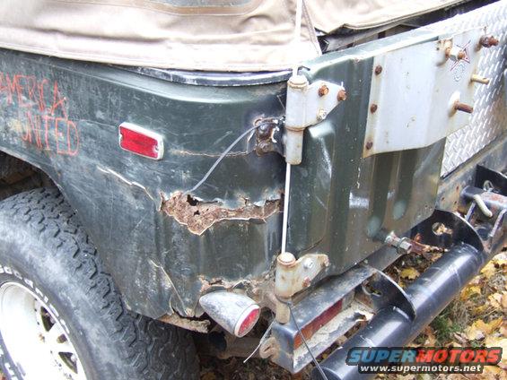 Green off-road vehicle rear quarter panel with heavy rust, red taillight, and "AMERICA UNITED" spray-painted on it