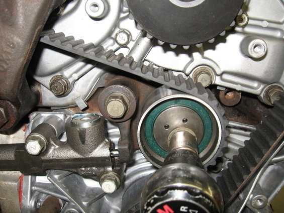 Close-up of engine timing belt and tensioner assembly with a socket wrench
