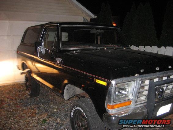 Black Ford Bronco parked in a driveway at night, front 3/4 view
