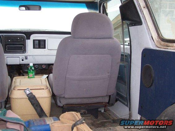 Interior view of a vehicle, showing seats, dashboard with radio, and a cooler. A bottle of Mountain Dew sits on the cooler