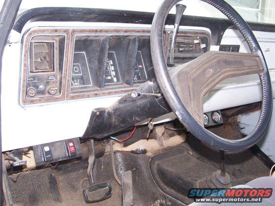1979 Ford Bronco interior dashboard with woodgrain trim, analog gauges, and a black steering wheel