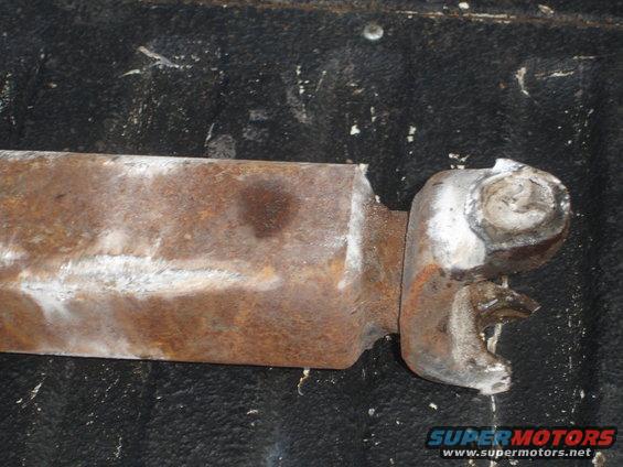 Rusted metal part with a silver connector, resting on a black textured surface