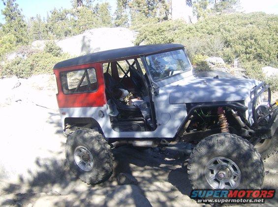 Off-road vehicle with red rear quarter panels and a black roof, lifted suspension, and large tires
