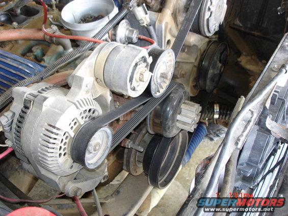 Engine belt tensioner and alternator assembly with visible dust and grime