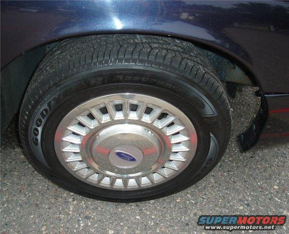 Dark blue car wheel with Goodyear Assurance tire and silver hubcap with Ford logo