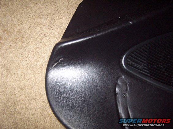 Black car door panel interior with speaker grille and visible damage. Text 'TREBLE' visible on speaker cover