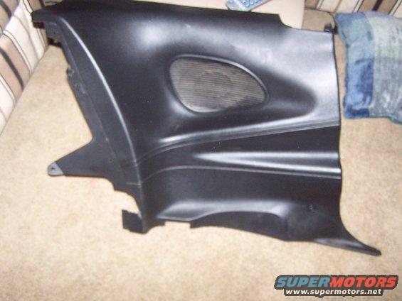 Black plastic interior trim piece with oval speaker grille, resting on carpet