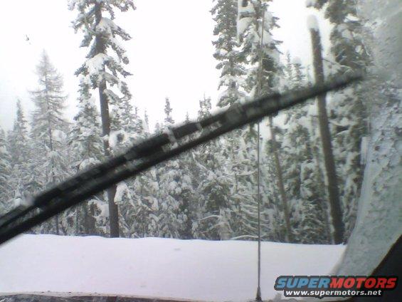 Windshield view of snowy forest with wiper blade