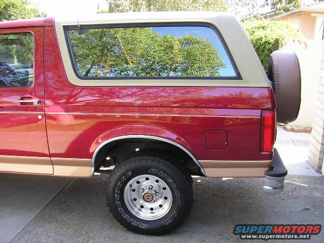 Side view of a red SUV with a tan top and a spare tire mounted on the rear door