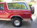 1994 Ford Bronco - The side profile of a red SUV shows its two-tone paint scheme and a rear-mounted spare tire.