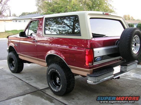 Red Ford Bronco with tan trim and a spare tire on the back