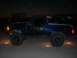 1994 Ford Bronco - A blue 1994 Ford Bronco is seen from the side at night, equipped with large off-road tires.