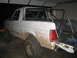 1996 Ford Bronco - Mud-covered 1996 Ford Bronco with a roll cage, parked indoors.