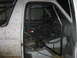 1996 Ford Bronco - The interior of a white off-road vehicle shows extensive roll cage modifications and mud-splattered exterior panels.