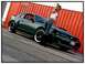 2002 Ford Mustang - A woman poses with a green Ford Mustang GT, parked outdoors with a large orange shipping container in the background.