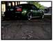2002 Ford Mustang - A dark green 2002 Ford Mustang is parked under an overpass, showing its rear end and custom wheels.